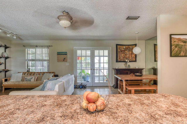 interior space featuring ceiling fan, french doors, rail lighting, and a textured ceiling