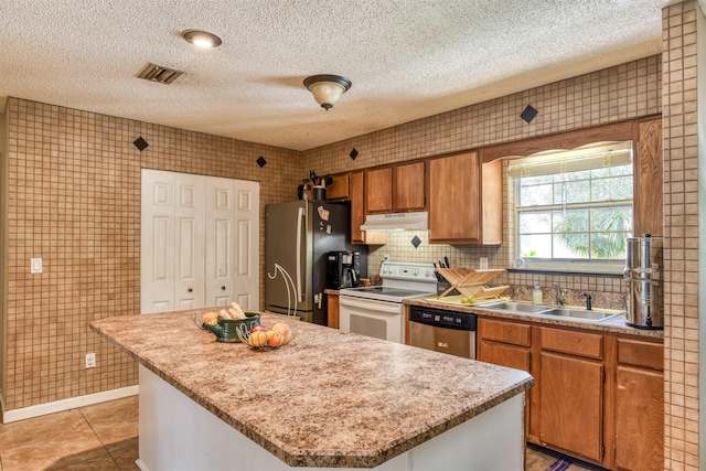 kitchen with backsplash, stainless steel appliances, sink, light tile patterned floors, and a center island