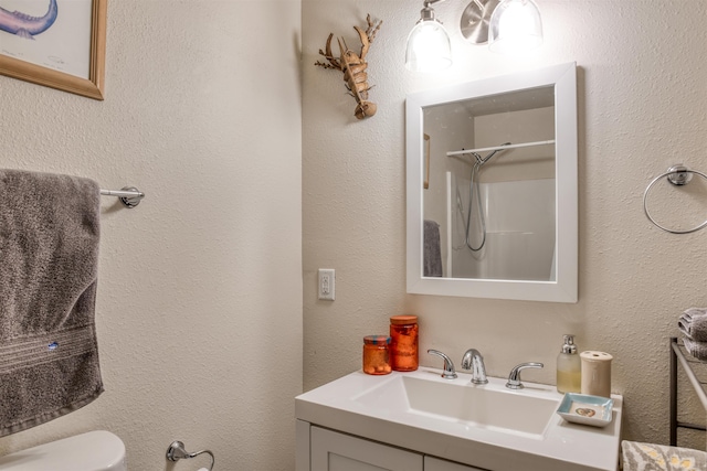 bathroom with a shower, vanity, and toilet