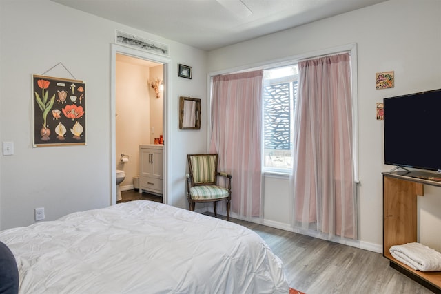 bedroom with ensuite bath and light wood-type flooring