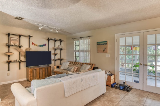 tiled living room with a healthy amount of sunlight, a textured ceiling, and french doors