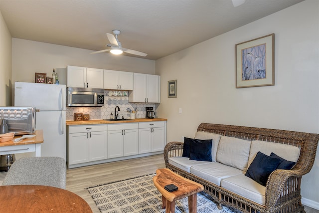 living room with ceiling fan, sink, and light hardwood / wood-style flooring