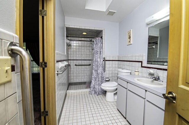 bathroom with tile patterned floors, vanity, tile walls, and toilet