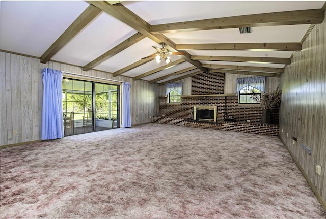 unfurnished living room featuring carpet floors, a brick fireplace, ceiling fan, and wood walls