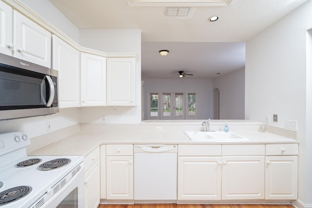 kitchen featuring white cabinetry, ceiling fan, sink, kitchen peninsula, and white appliances