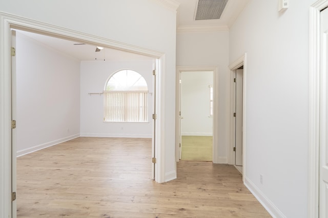 corridor with ornamental molding and light hardwood / wood-style flooring