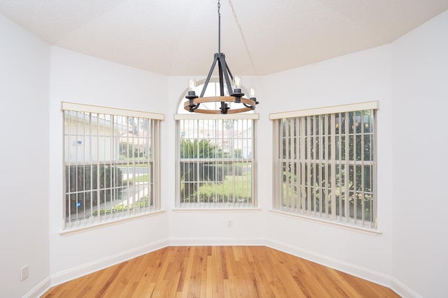 unfurnished dining area with wood-type flooring and a chandelier