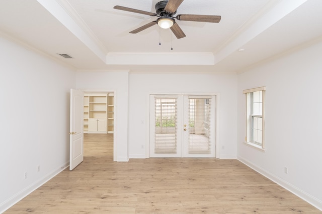 spare room featuring ceiling fan, french doors, a raised ceiling, light hardwood / wood-style flooring, and crown molding