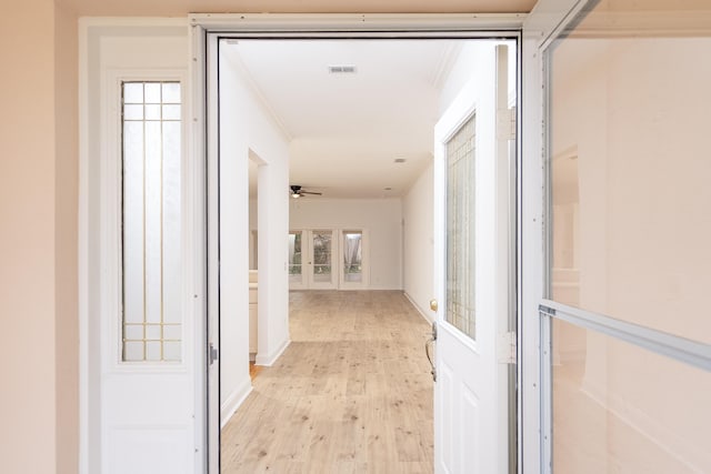 hallway with crown molding, light hardwood / wood-style flooring, a wealth of natural light, and french doors