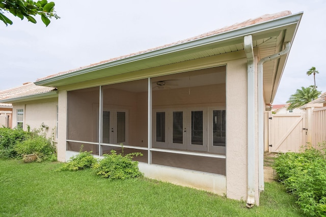 back of house with a yard, a sunroom, and french doors