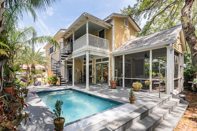 rear view of property with a sunroom, ceiling fan, and a balcony