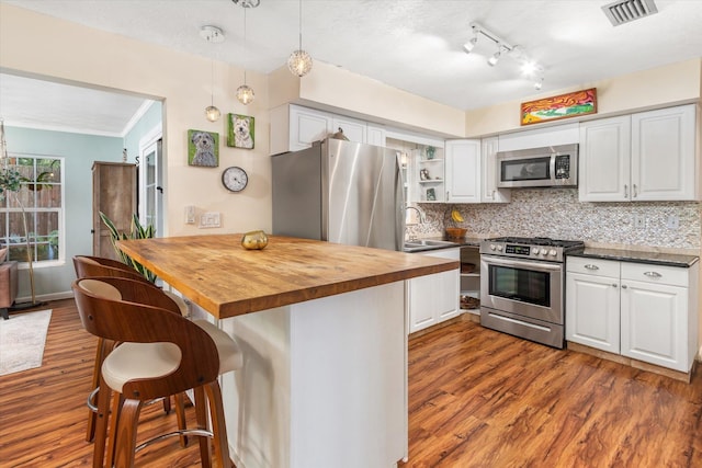 605 A St, Saint Augustine, FL 32080 - kitchen featuring stainless steel appliances, butcher block countertops, dark wood-style floors, a breakfast bar area, and white cabinets