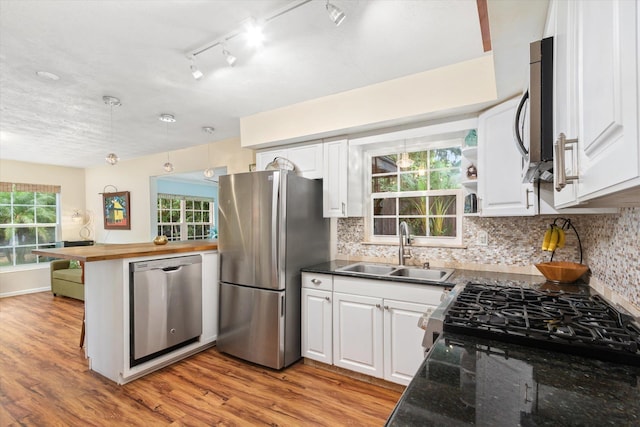 605 A St, Saint Augustine, FL 32080 - kitchen with stainless steel appliances, white cabinetry, light wood-type flooring, and decorative backsplash