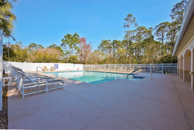 community pool with a patio area and fence