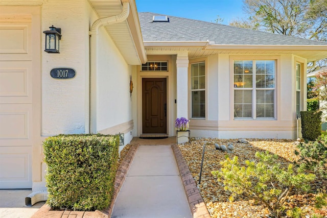 property entrance with an attached garage, stucco siding, and roof with shingles