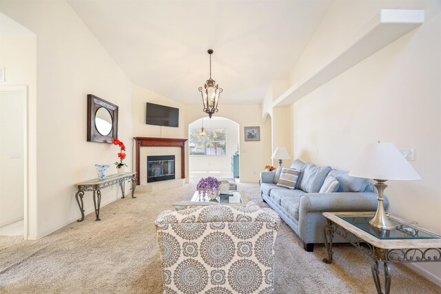 living area featuring carpet floors, arched walkways, vaulted ceiling, a chandelier, and a tile fireplace