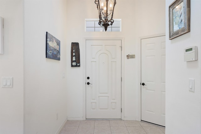 foyer entrance featuring light tile patterned floors, baseboards, and a notable chandelier