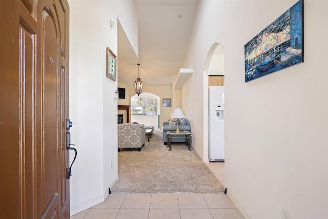 hallway featuring light carpet, a high ceiling, light tile patterned flooring, and arched walkways