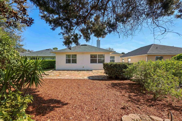 rear view of property with a chimney and stucco siding