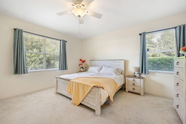 bedroom featuring light colored carpet, ceiling fan, and baseboards