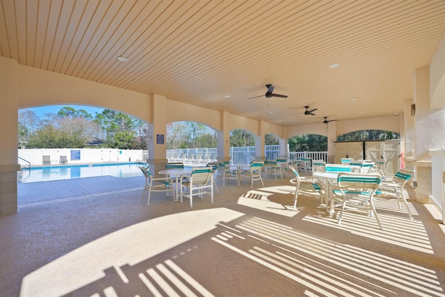 view of patio with a ceiling fan, outdoor dining space, a fenced backyard, and a community pool