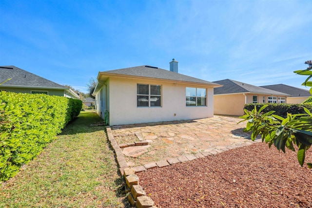 back of property featuring a patio, a chimney, and stucco siding