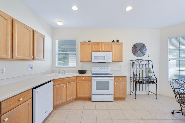 kitchen with white appliances, light tile patterned floors, a sink, and light brown cabinetry