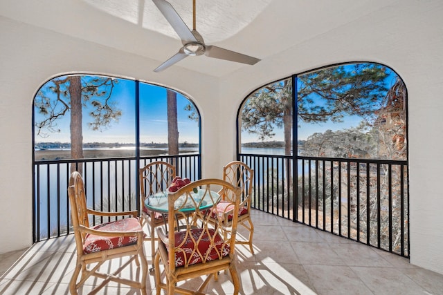 sunroom / solarium with ceiling fan and a water view