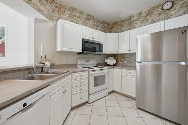 kitchen featuring appliances with stainless steel finishes, light tile patterned floors, white cabinetry, and sink