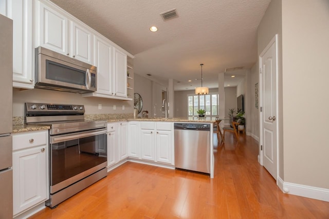 517 Weeping Willow Ln, Saint Augustine, FL 32080 - kitchen with stainless steel appliances, a peninsula, white cabinetry, light wood-style flooring, and recessed lighting