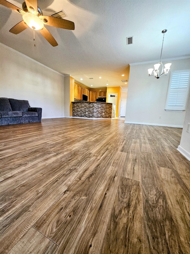 unfurnished living room with baseboards, a textured ceiling, ornamental molding, and wood finished floors