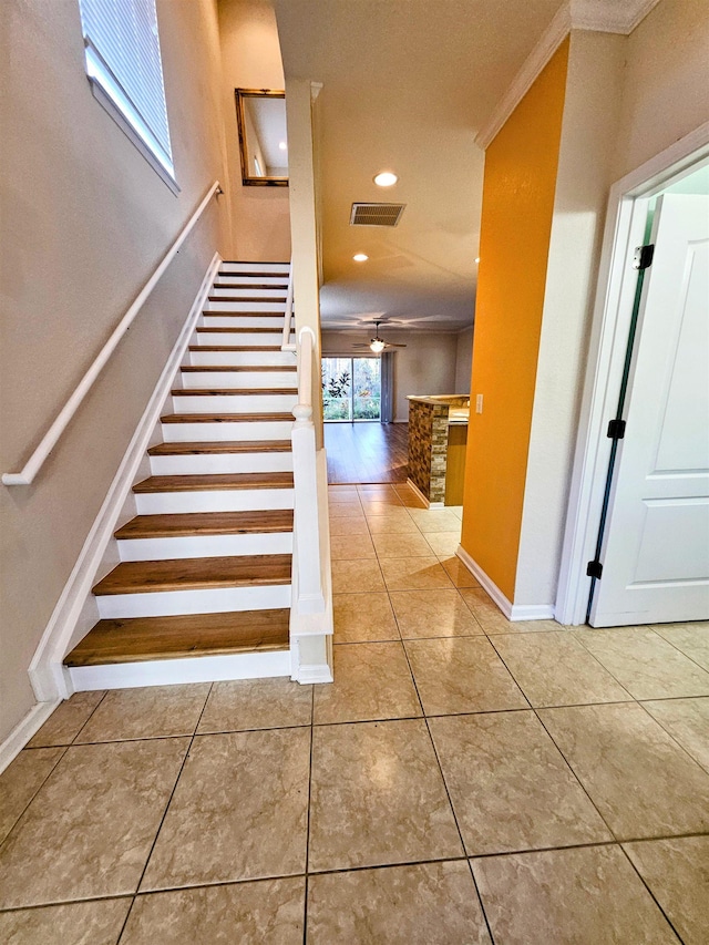 stairway featuring tile patterned flooring, visible vents, a ceiling fan, and ornamental molding