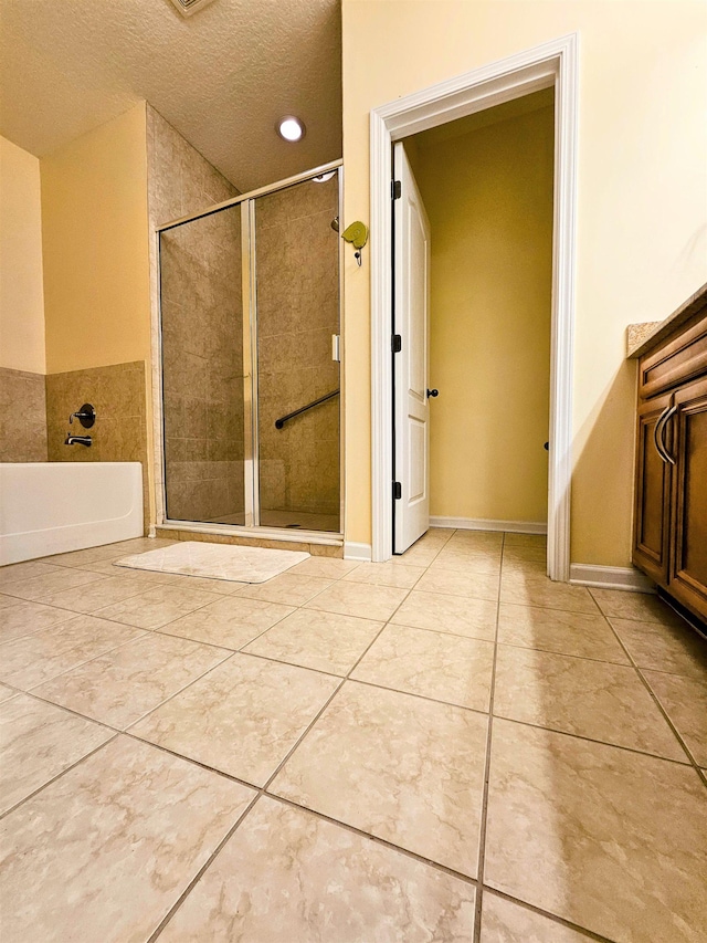 full bathroom with a stall shower, a garden tub, a textured ceiling, and tile patterned floors