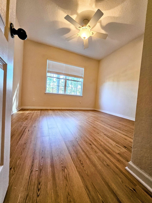 unfurnished room featuring baseboards, a textured ceiling, a ceiling fan, and wood finished floors