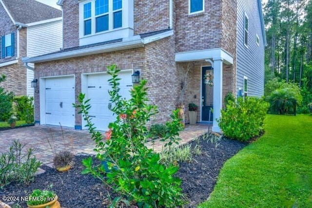 view of front of home with a garage, driveway, a front lawn, and brick siding