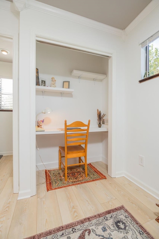 dining area featuring baseboards, built in desk, crown molding, and wood finished floors