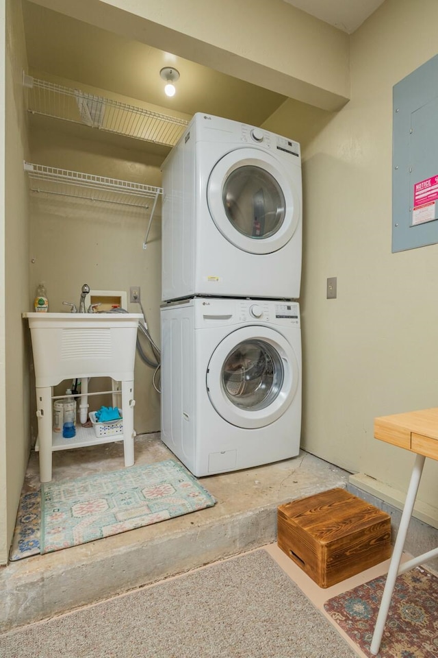 laundry area featuring laundry area, electric panel, and stacked washing maching and dryer