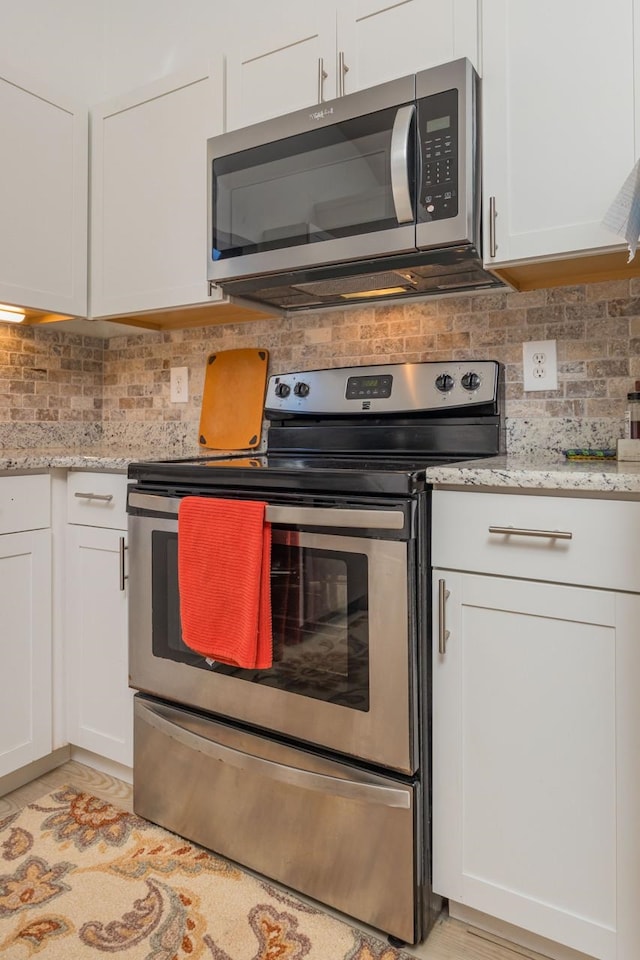 kitchen featuring stainless steel appliances, white cabinetry, and tasteful backsplash