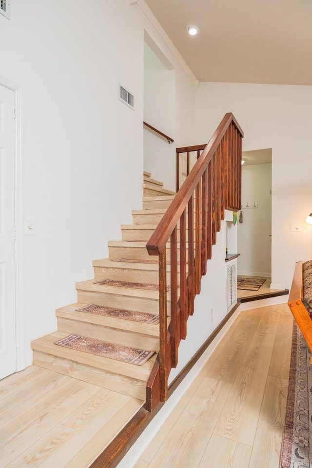 stairs featuring visible vents, wood finished floors, and ornamental molding