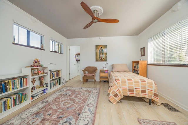 bedroom with hardwood / wood-style flooring, multiple windows, visible vents, and ornamental molding