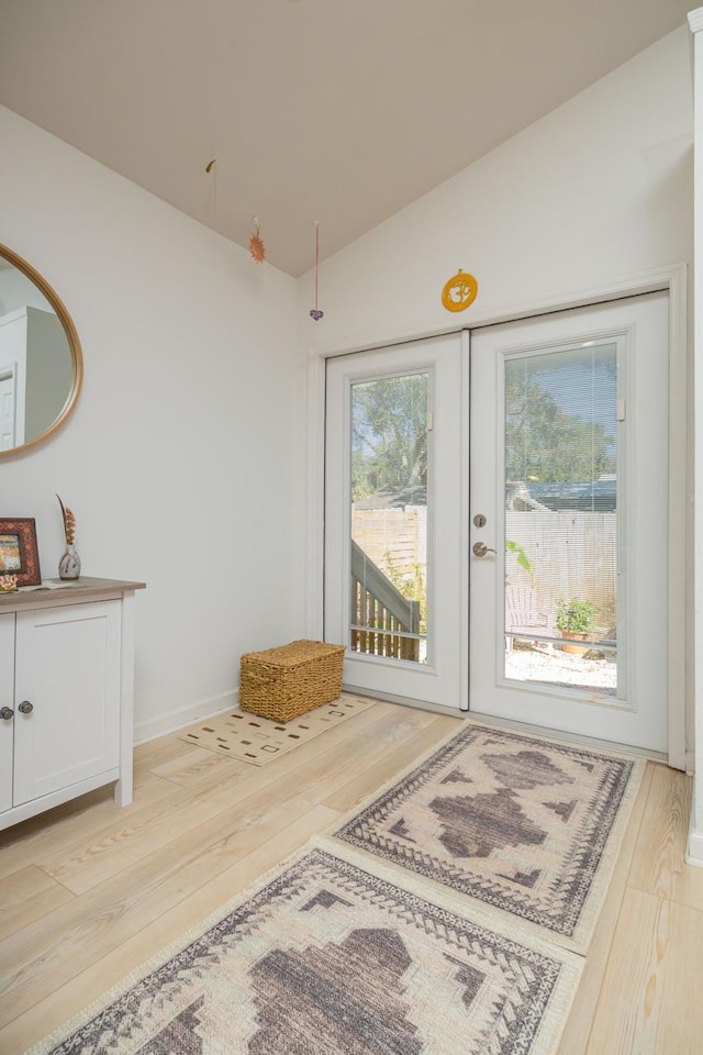 doorway with vaulted ceiling, french doors, and light wood-type flooring