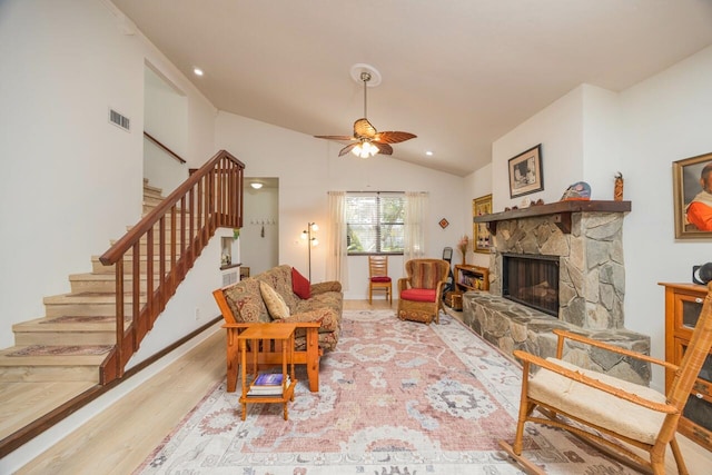 living room featuring a fireplace, wood finished floors, visible vents, vaulted ceiling, and stairway