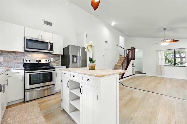 1684 Leon St, Saint Augustine, FL 32080 - kitchen featuring stainless steel appliances, decorative backsplash, ceiling fan, light wood-type flooring, and high vaulted ceiling