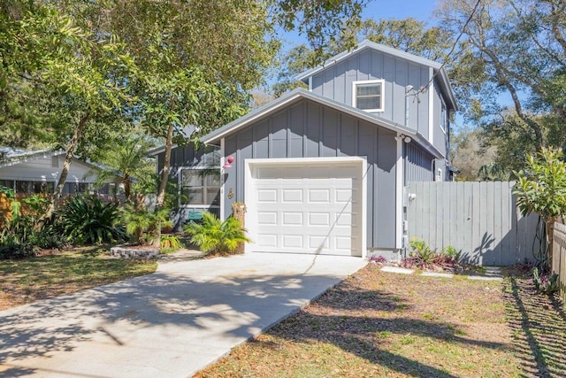 view of front of house with board and batten siding, concrete driveway, and fence