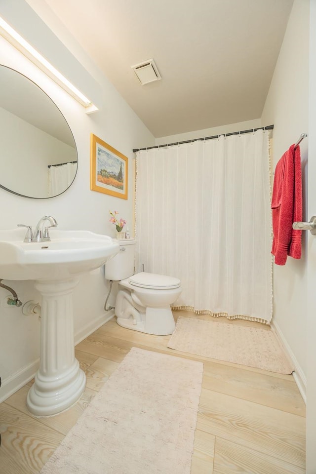 full bathroom with baseboards, visible vents, toilet, wood finished floors, and vaulted ceiling