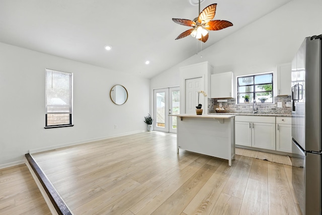 1684 Leon St, Saint Augustine, FL 32080 - kitchen featuring stainless steel refrigerator with ice dispenser, a kitchen breakfast bar, light countertops, lofted ceiling, and light wood-type flooring