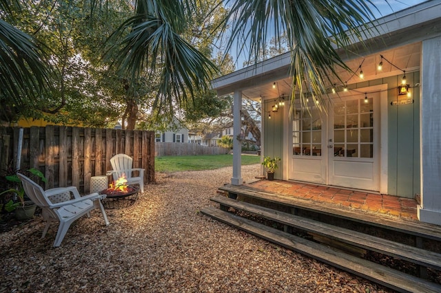 view of yard with fence, french doors, and a fire pit