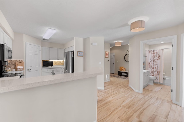 kitchen featuring light countertops, decorative backsplash, stainless steel appliances, and white cabinets