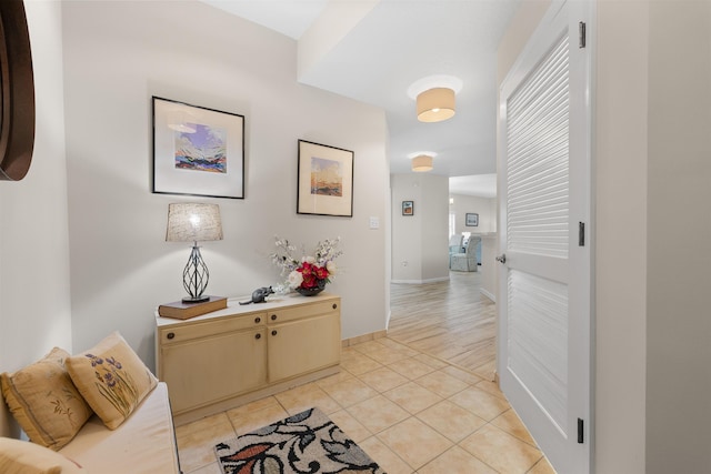 hall featuring baseboards, a wealth of natural light, and light tile patterned floors