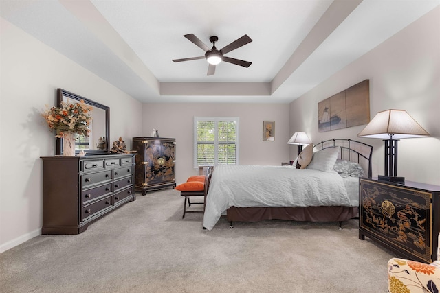 carpeted bedroom with baseboards, a ceiling fan, and a tray ceiling